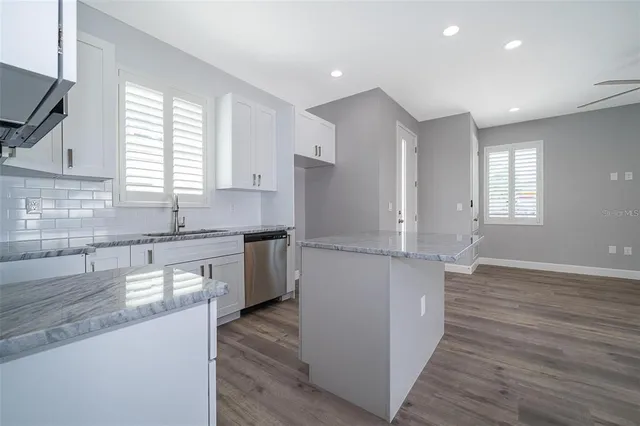 a kitchen with granite countertop a sink wooden floor and stainless steel appliances
