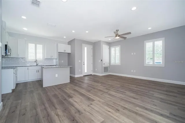 a large kitchen with stainless steel appliances granite countertop a stove a sink dishwasher and a oven with white cabinets