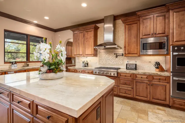 a kitchen with kitchen island granite countertop a sink counter top space appliances and cabinets