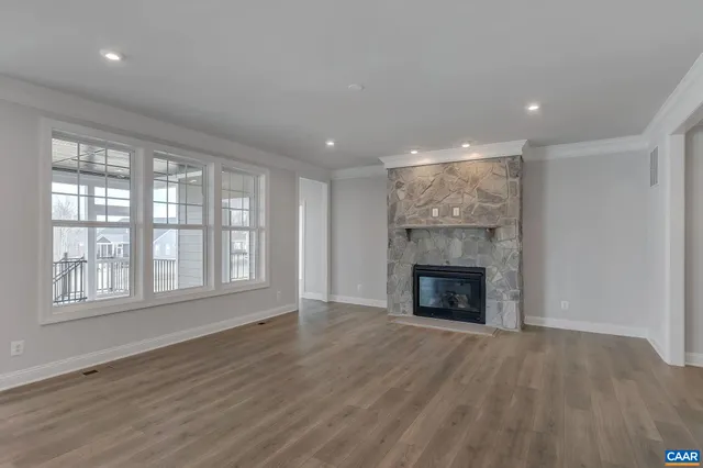an empty room with wooden floor fireplace and windows
