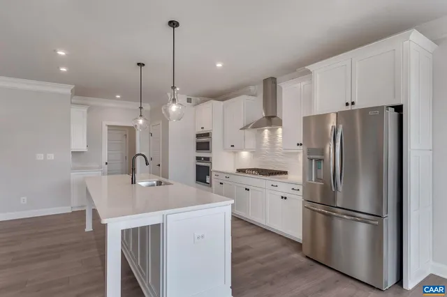 a kitchen with stainless steel appliances a refrigerator a sink a stove a microwave and wooden floor