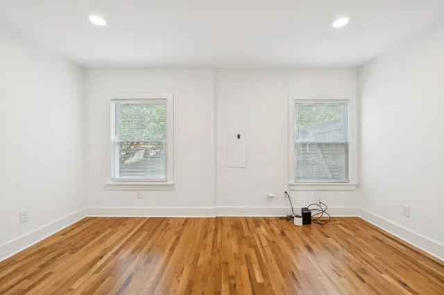a view of a hallway with wooden floor and a bathroom