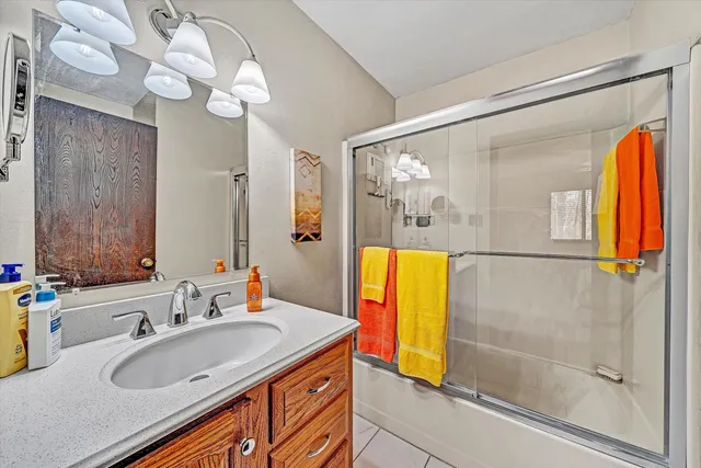 a bathroom with a sink vanity granite tub shower and mirror