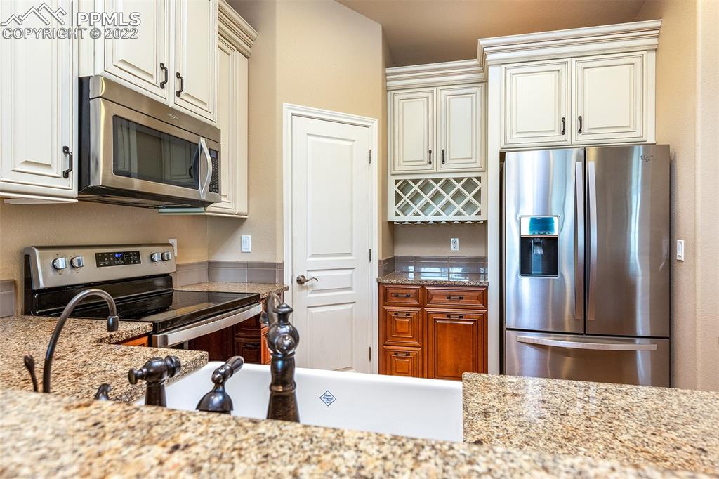 2361 Conservatory Point Colorado Springs, CO 80918 - Photo 9 of 50 a kitchen with stainless steel appliances kitchen island granite countertop a refrigerator and a stove top oven