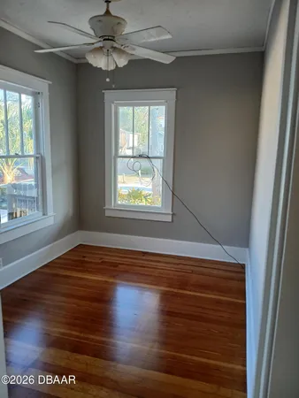 a view of empty room with wooden floor and fan