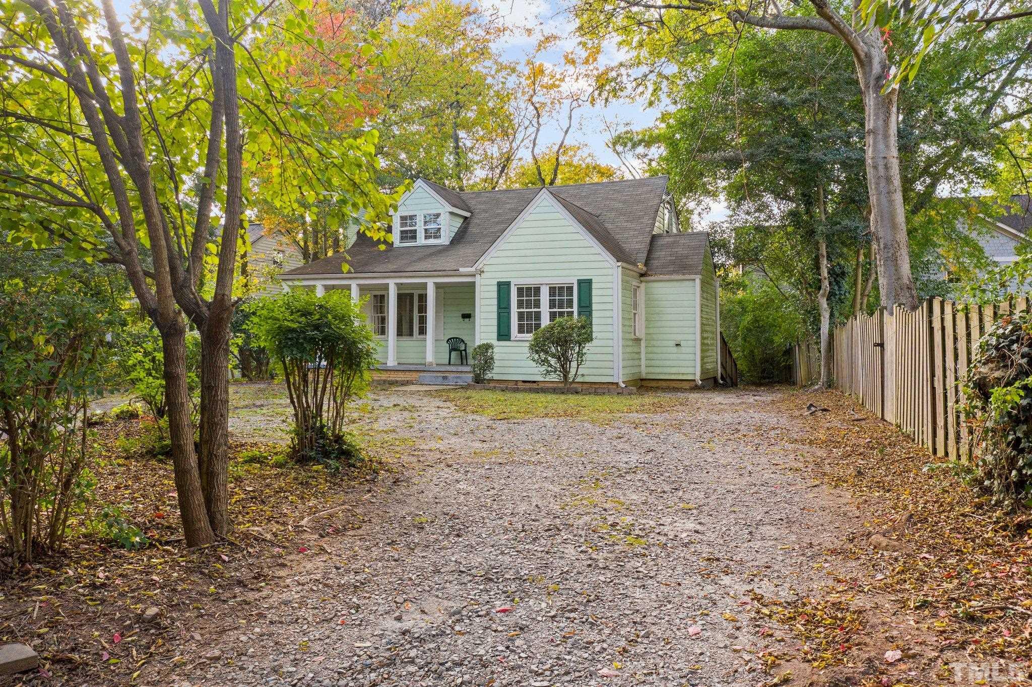 a front view of a house with a garden and trees