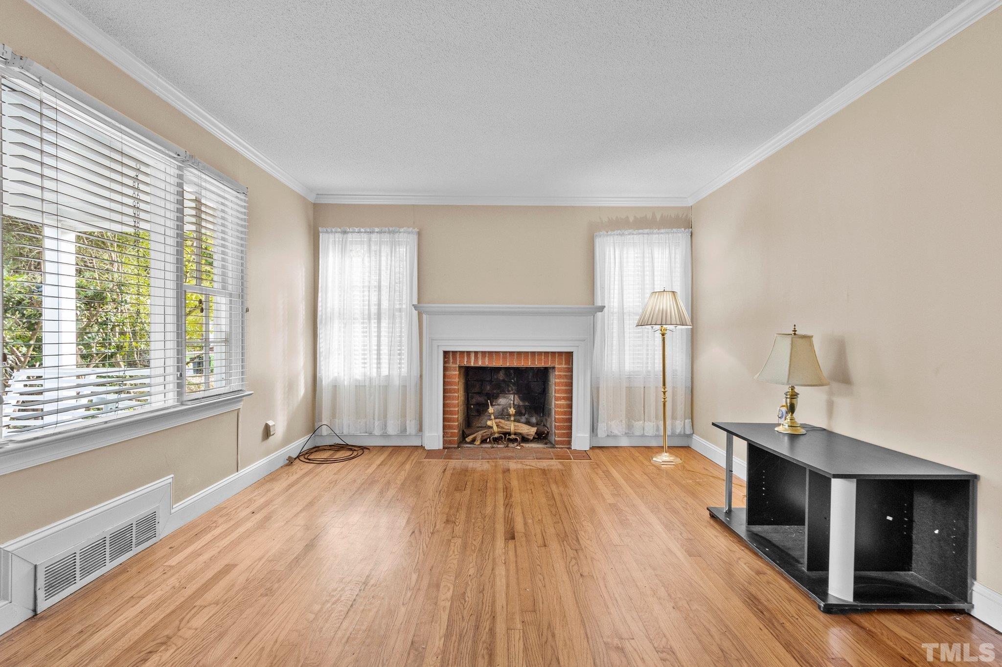 1713 Oberlin Road Raleigh, NC 27608 - Photo 5 of 34 a view of an empty room with wooden floor fireplace and a window
