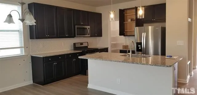 a kitchen with stainless steel appliances granite countertop a refrigerator and a stove top oven