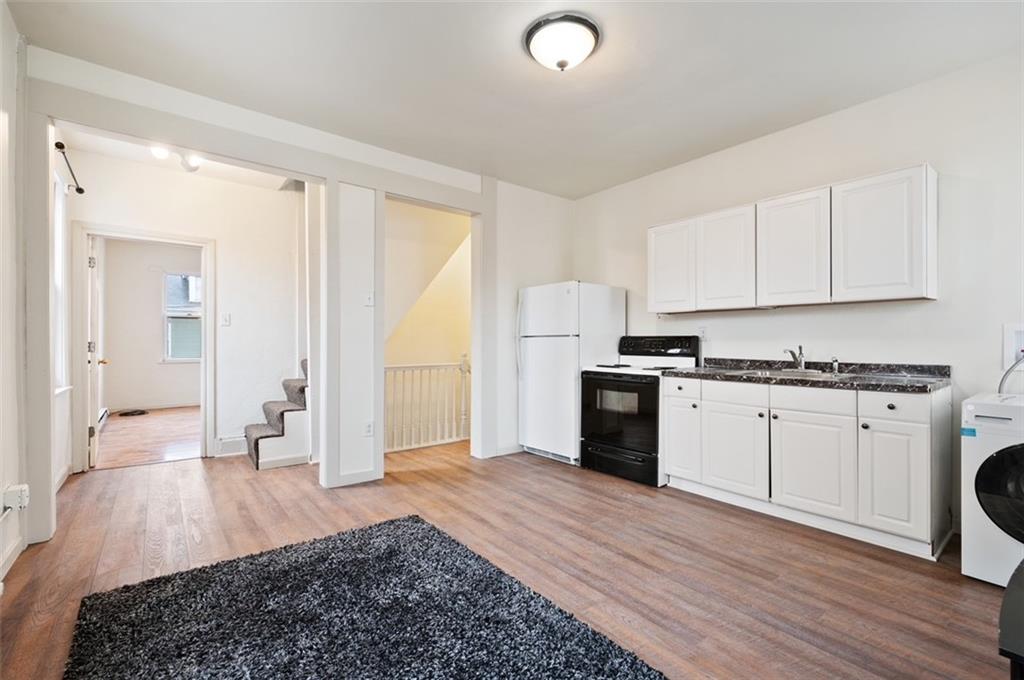 4827 Sciota Street Pittsburgh, PA 15224 - Photo 8 of 19 a large white kitchen with granite countertop a stove a sink a refrigerator and white cabinets with wooden floor
