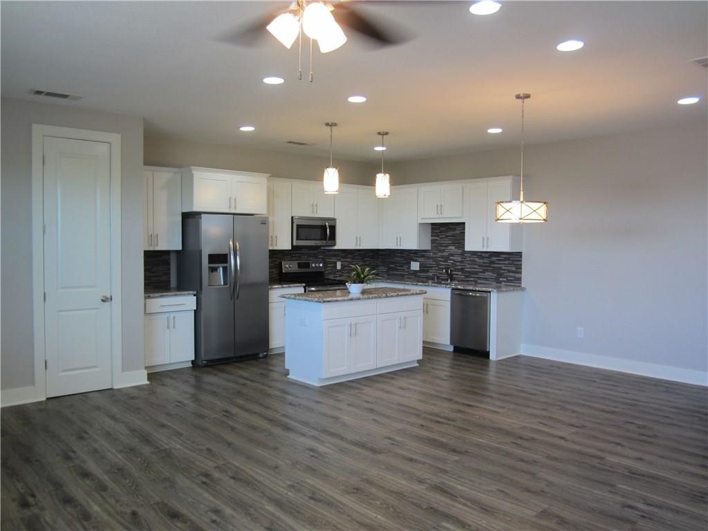 a kitchen with stainless steel appliances kitchen island granite countertop a stove a refrigerator and a microwave