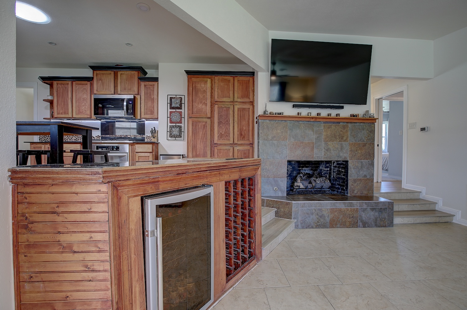1902 East 18th Street Georgetown, TX 78626 - Photo 40 of 40 Family room/Kitchen open floor plan featuring wine cooler, wood finish cabinetry, stainless steel appliances, light tile patterned flooring, and a tile fireplace