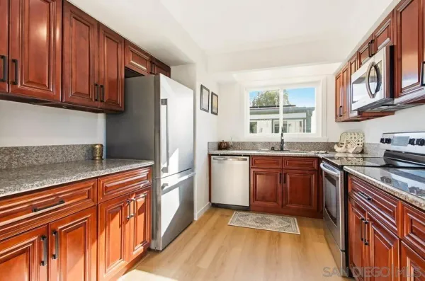 a kitchen with stainless steel appliances granite countertop a stove a sink dishwasher and a refrigerator with wooden cabinets