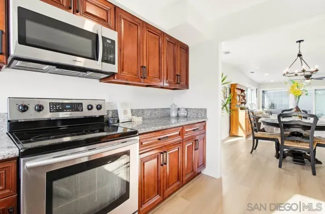 a kitchen with stainless steel appliances granite countertop a refrigerator a stove a dining table and chairs with wooden floor