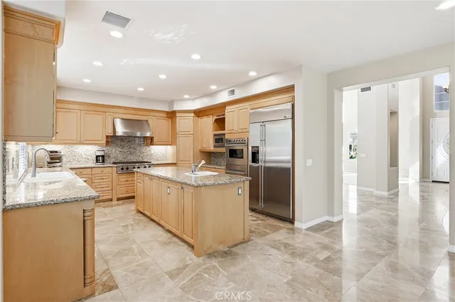 a large kitchen with stainless steel appliances kitchen island granite countertop a large counter top and a stove