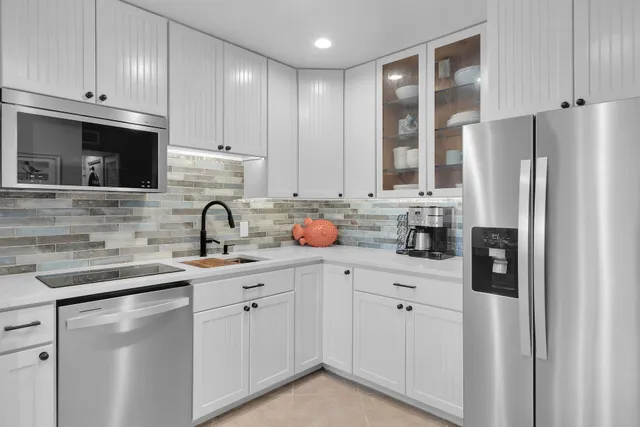 a kitchen with white cabinets and refrigerator