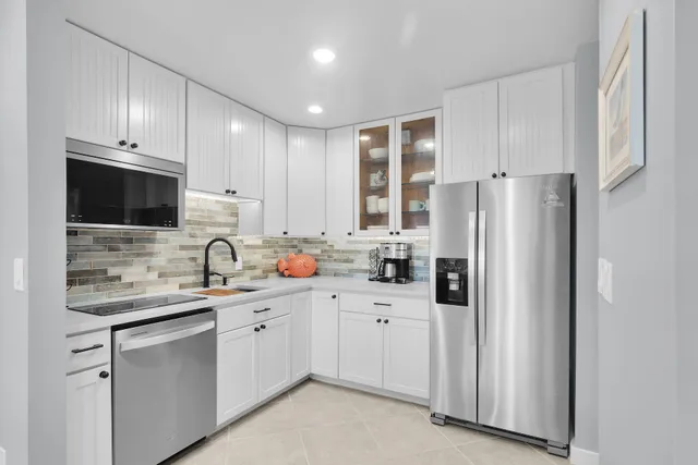 a kitchen with stainless steel appliances a sink a stove a microwave a refrigerator and a table