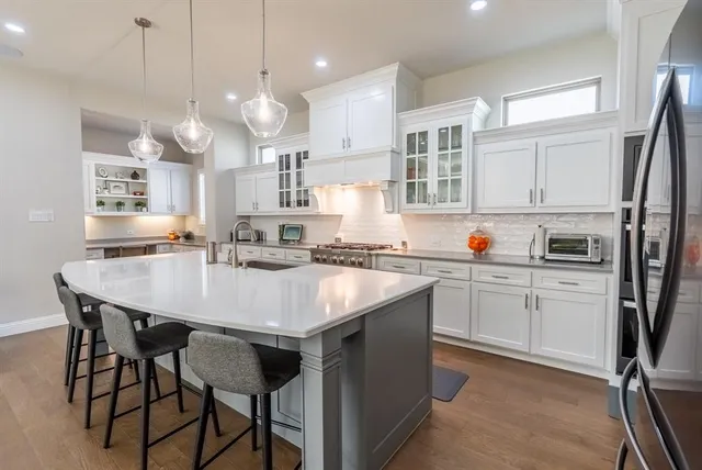 a kitchen with stainless steel appliances granite countertop a table chairs refrigerator and microwave