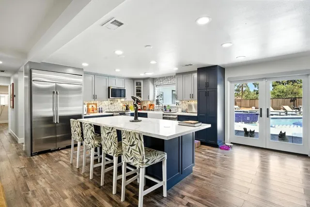 a kitchen with stainless steel appliances a dining table chairs and wooden floor