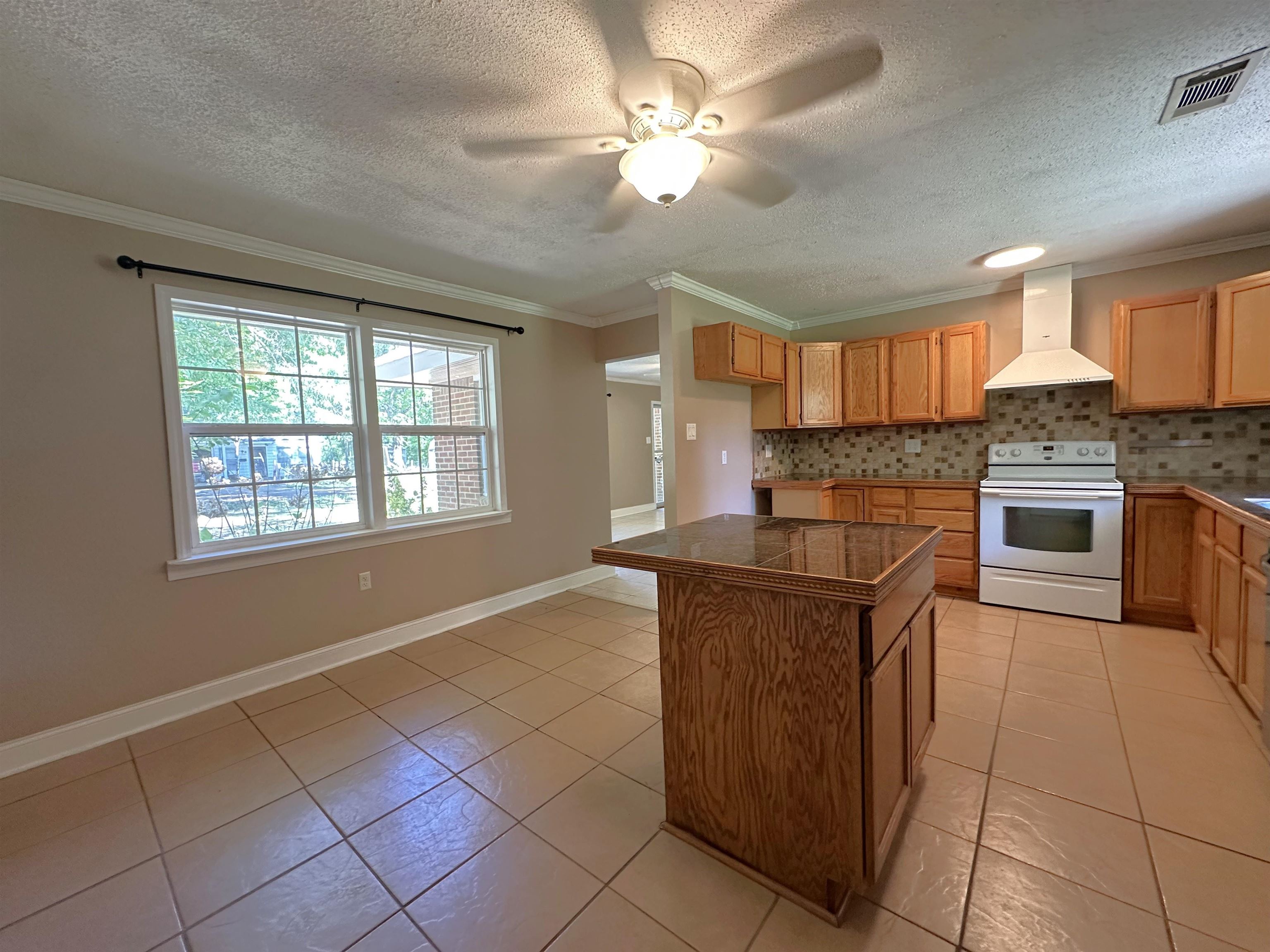 7874 Shamrock Road Millington, TN 38053 - Photo 4 of 17 Kitchen area with a built-in island featuring a dark countertop, wood-finish cabinetry, a tiled backsplash, a white range with a matching range hood, and tile flooring