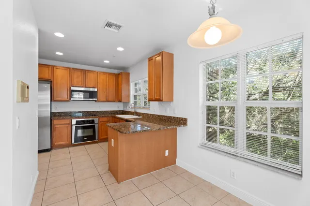 a kitchen with stainless steel appliances granite countertop a refrigerator a stove and a sink with wooden cabinets