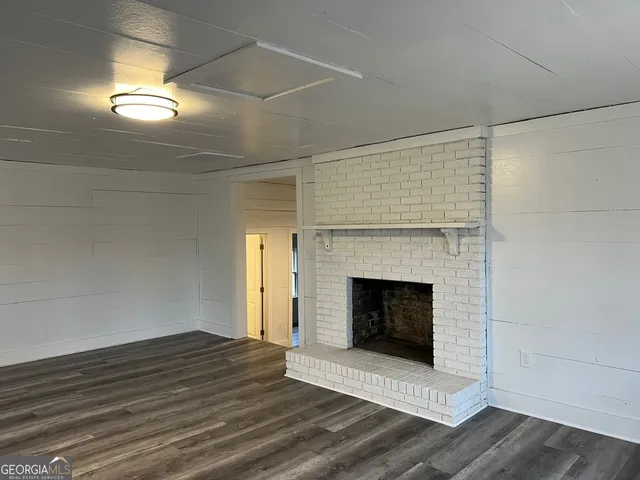 a view of a livingroom with wooden floor a fireplace and windows