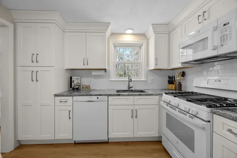 a kitchen with granite countertop white cabinets and white appliances