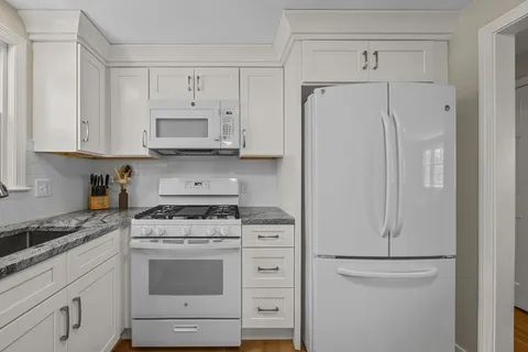 a kitchen with white cabinets and white appliances