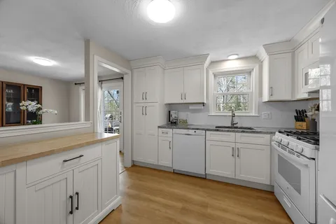 a kitchen with white cabinets appliances a sink and a window