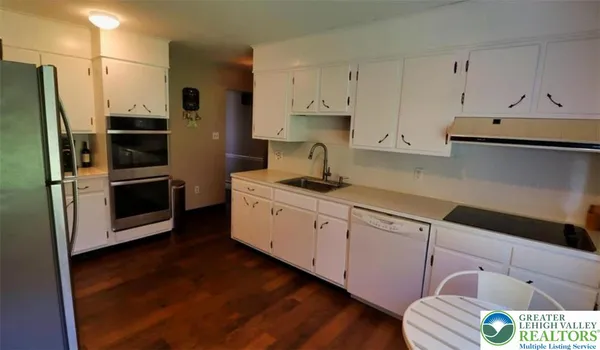 a kitchen with cabinets stainless steel appliances and wooden floor