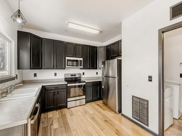 a kitchen with a sink a stove a refrigerator and black cabinets