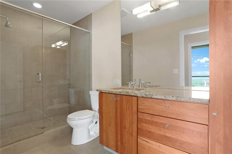 3325 Piedmont Road Northeast, Unit 2404 Atlanta, GA 30305 - Photo 19 of 36 a bathroom with a granite countertop sink toilet a mirror and shower