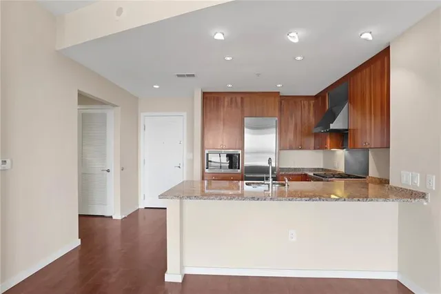 a kitchen with kitchen island granite countertop wooden cabinets a refrigerator and a sink