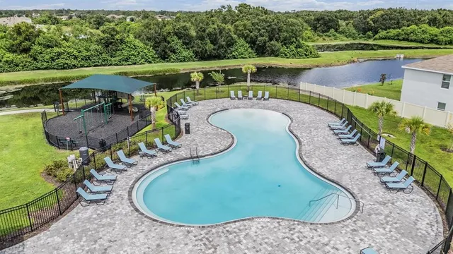 an aerial view of a swimming pool with a yard and outdoor seating