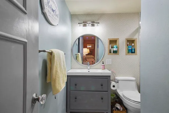 a bathroom with a toilet sink vanity and mirror