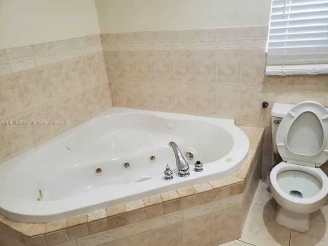 a bathroom with a bathtub sink mirror and toilet