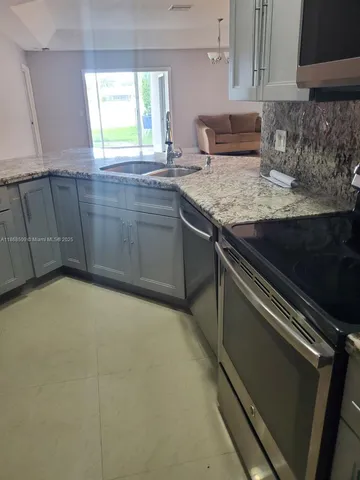 a kitchen with granite countertop a sink and a stove