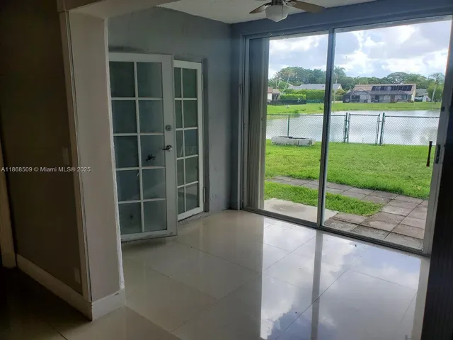 a view of an empty room with a large window and wooden floor