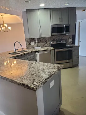 a kitchen with granite countertop a sink and stainless steel appliances