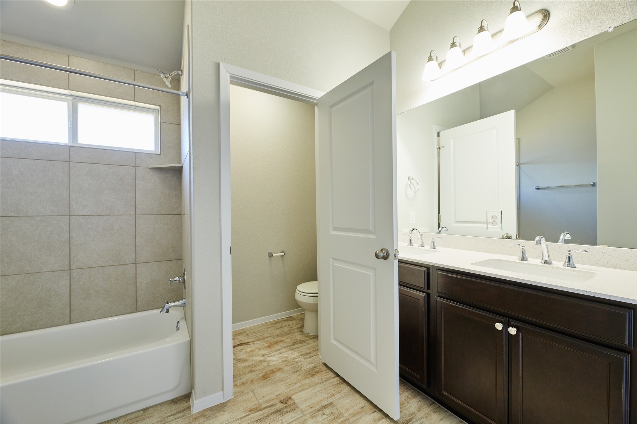 303 Trailside Lane Bastrop, TX 78602 - Photo 14 of 25 Full bathroom featuring double vanity, bathing tub / shower combination, and light wood-style flooring