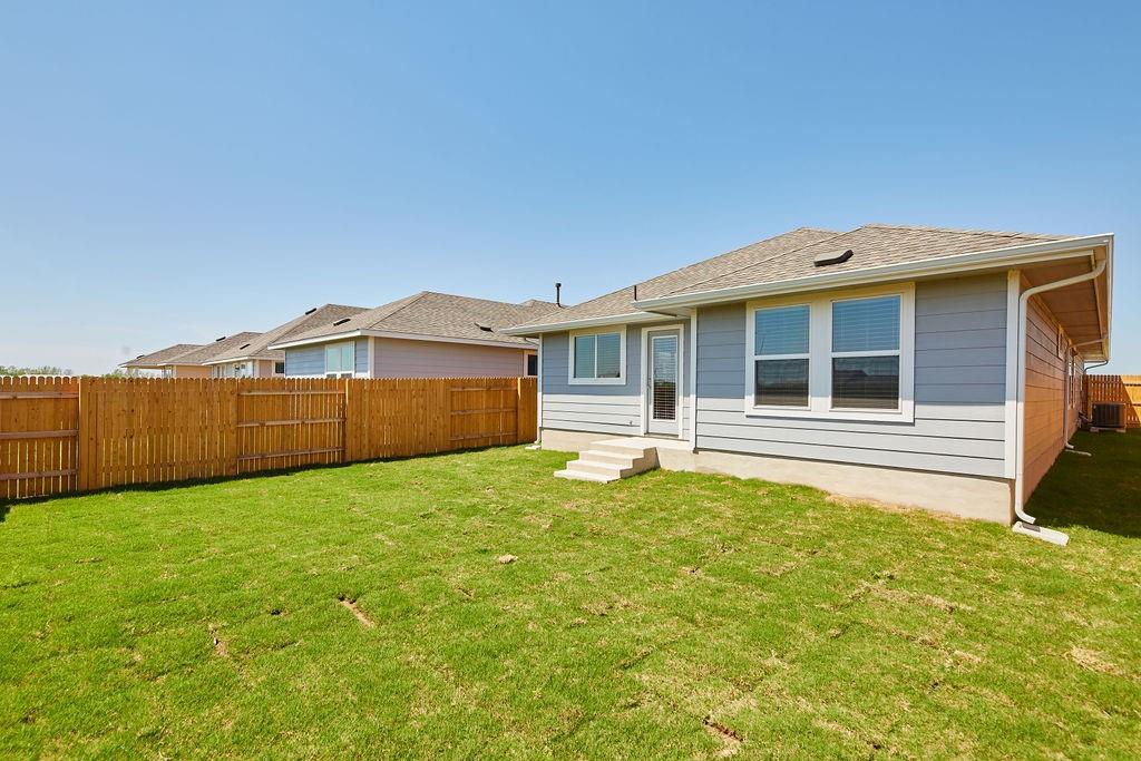 303 Trailside Lane Bastrop, TX 78602 - Photo 22 of 25 Back of property with a fenced backyard and a shingled roof
