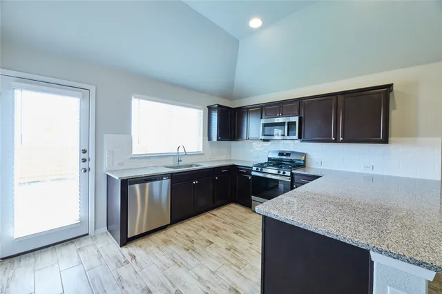 a kitchen with stainless steel appliances granite countertop a sink stove and microwave