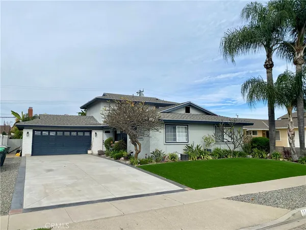 a front view of a house with a garden and palm tree