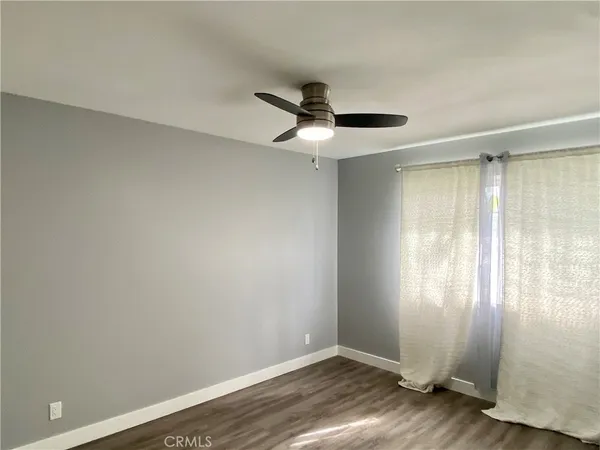 an empty room with wooden floor cabinet and windows