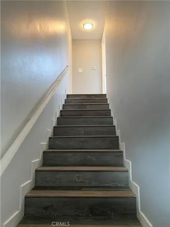 a view of a hallway with wooden floor and a bathroom