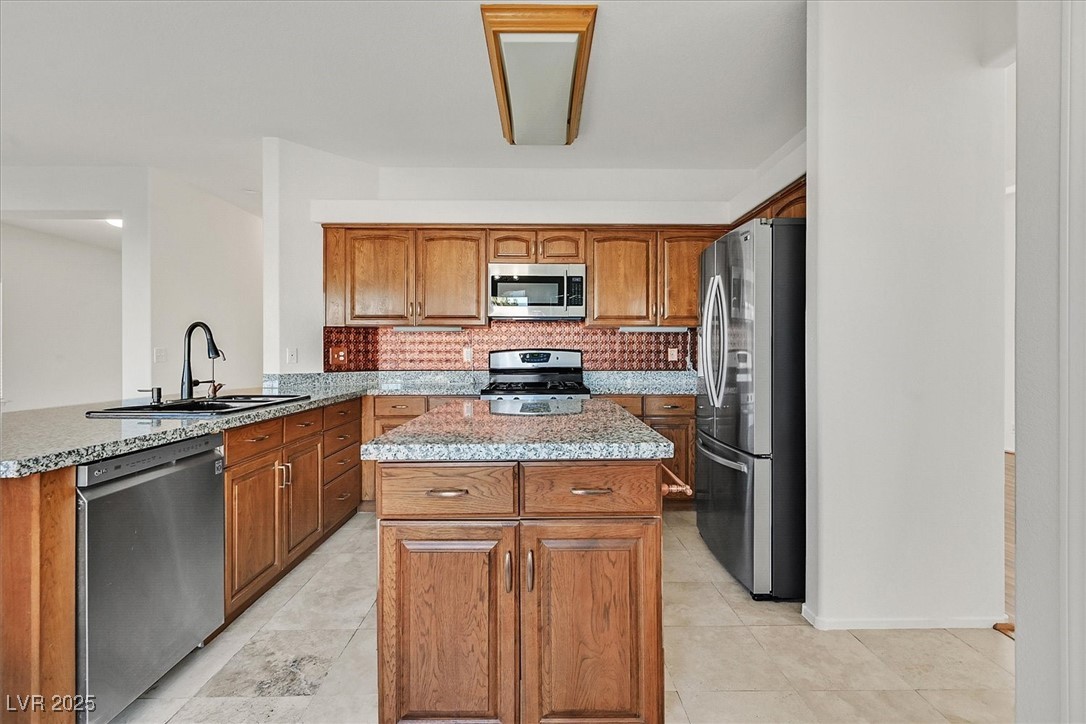 234 Highgate Street Henderson, NV 89074 - Photo 7 of 22 Kitchen with appliances with stainless steel finishes, brown cabinets, and a center island