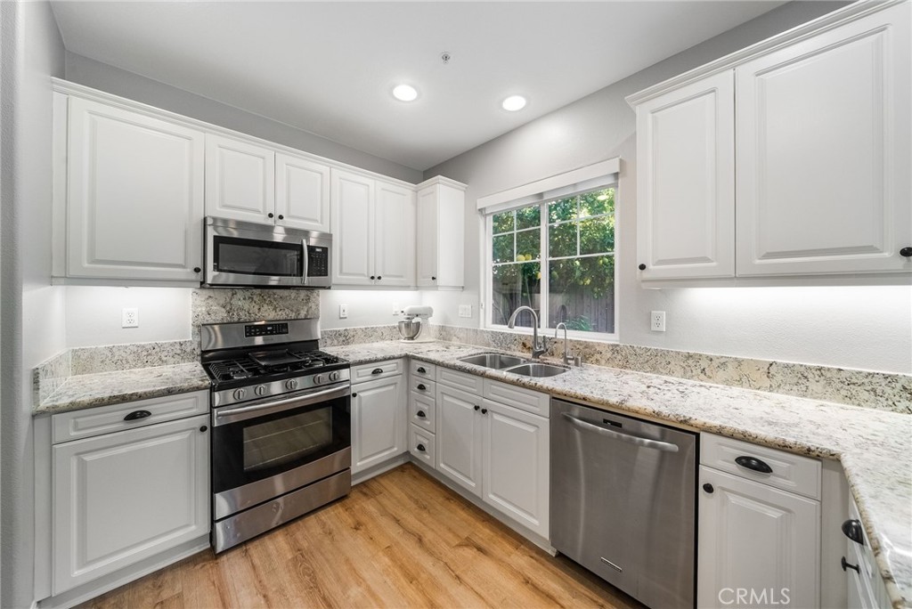 9 Flowerdale Ladera Ranch, CA 92694 - Photo 16 of 54 a kitchen with granite countertop white cabinets appliances a sink and a window