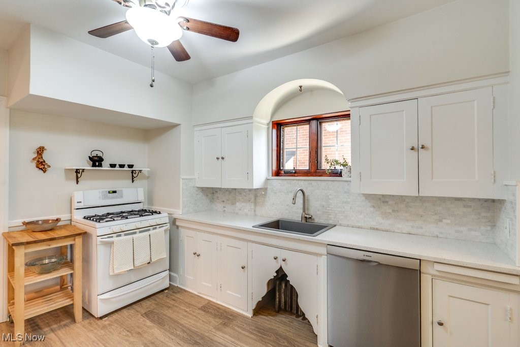 3849 Faversham Road Cleveland, OH 44118 - Photo 14 of 44 Kitchen with white gas stove, dishwasher, decorative backsplash, light wood-style floors, and white cabinetry