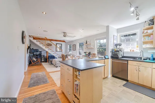 a kitchen with stainless steel appliances granite countertop a sink a refrigerator and a wooden floor