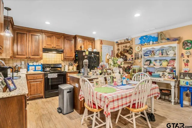 a kitchen with stainless steel appliances granite countertop a table chairs and a refrigerator