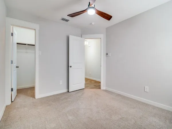 an empty room with closet and a ceiling fan